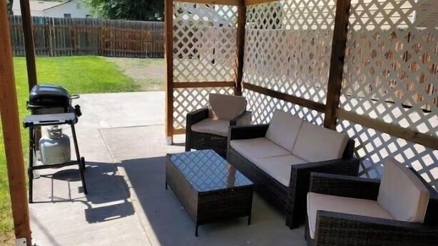 Eine Terrasse im Freien mit Korbmöbeln und einem Grill.