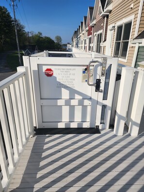 A gated entrance with a chair lift, a stop sign, and a posted sign with rules.