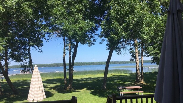A deck with outdoor furniture, a view of a lake, and trees.