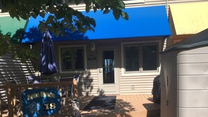 A house with a blue awning, a welcome sign, and a number 18 sign.