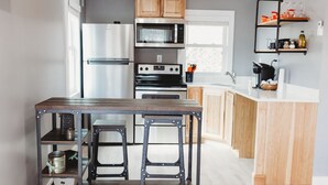 Una cocina moderna con una isla central, armarios de madera y electrodomésticos de acero inoxidable, incluyendo un horno empotrado.