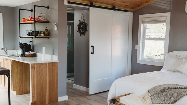 Un dormitorio con cama, mesita de noche, armario y ventana con vistas.