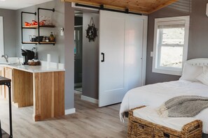 Une chambre à coucher comprenant un lit, une table de chevet, une armoire et une fenêtre donnant sur un beau paysage.