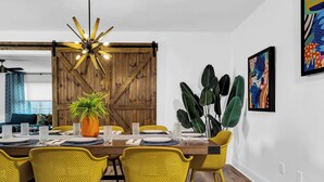A dining area with a wooden table, yellow chairs, a potted plant, and a ceiling fan. - The Blue Door Bentonville is an ideal Bike In/Bike Out location, close to dwtwn. (Bentonville)