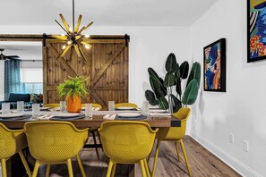 A dining area with a wooden table, yellow chairs, a potted plant, and a ceiling fan. - The Blue Door Bentonville is an ideal Bike In/Bike Out location, close to dwtwn. (Bentonville)