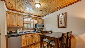 Une cuisine avec des meubles de rangement en bois, un four à micro-ondes, un lave-vaisselle et une table à manger avec des chaises.