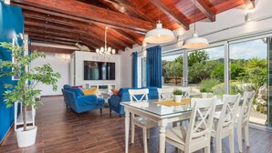 A modern living room with a TV, sofas, and a dining area with a glass table and chairs. - Luxurious home in Nerezine with WiFi (Nerezine)