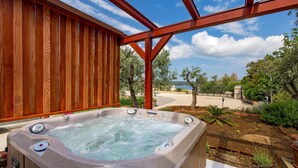 A hot tub under a wooden pergola with a view of a landscaped garden and the sea. - Luxurious home in Nerezine with WiFi (Nerezine)