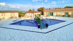 A swimming pool with a tiled deck, surrounded by stone buildings with green shutters, under a clear sky. - Luxurious home in Nerezine with WiFi (Nerezine)