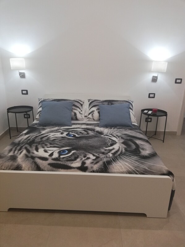 A bed with a tiger print bedspread, two bedside tables, and wall-mounted lights.