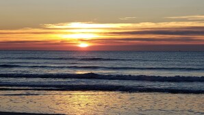 Un atardecer sobre el océano con olas acercándose a la orilla.