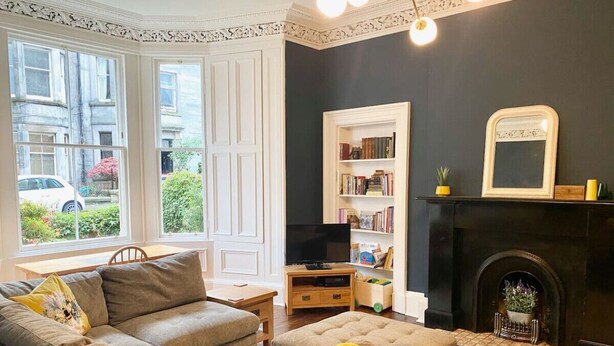 A cozy living room with a sectional sofa, a fireplace, a bookshelf, and a television. - Meadows Sanctuary-Perfect base for exploring Edinburgh, private  garden (Edinburgh)