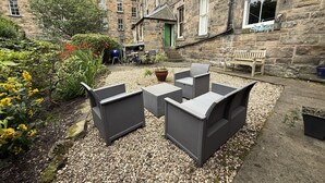 A courtyard with outdoor seating, a green door, and stone buildings in the background. - Meadows Sanctuary-Perfect base for exploring Edinburgh, private  garden (Edinburgh)