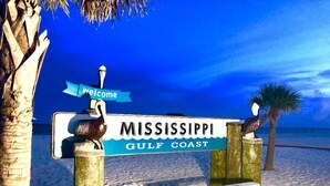 Schild zur Begrüßung der Mississippi Golfküste mit einer hölzernen Bank und Palmen.