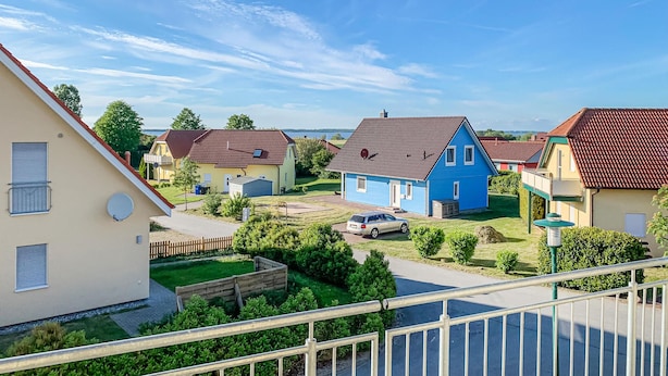 Ett bostadsområde med hus, en bil och en klar himmel.