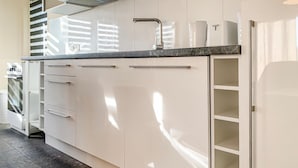 Ett modernt kök med vita skåp, en rostfri köksfläkt och en bänkskiva i marmor.