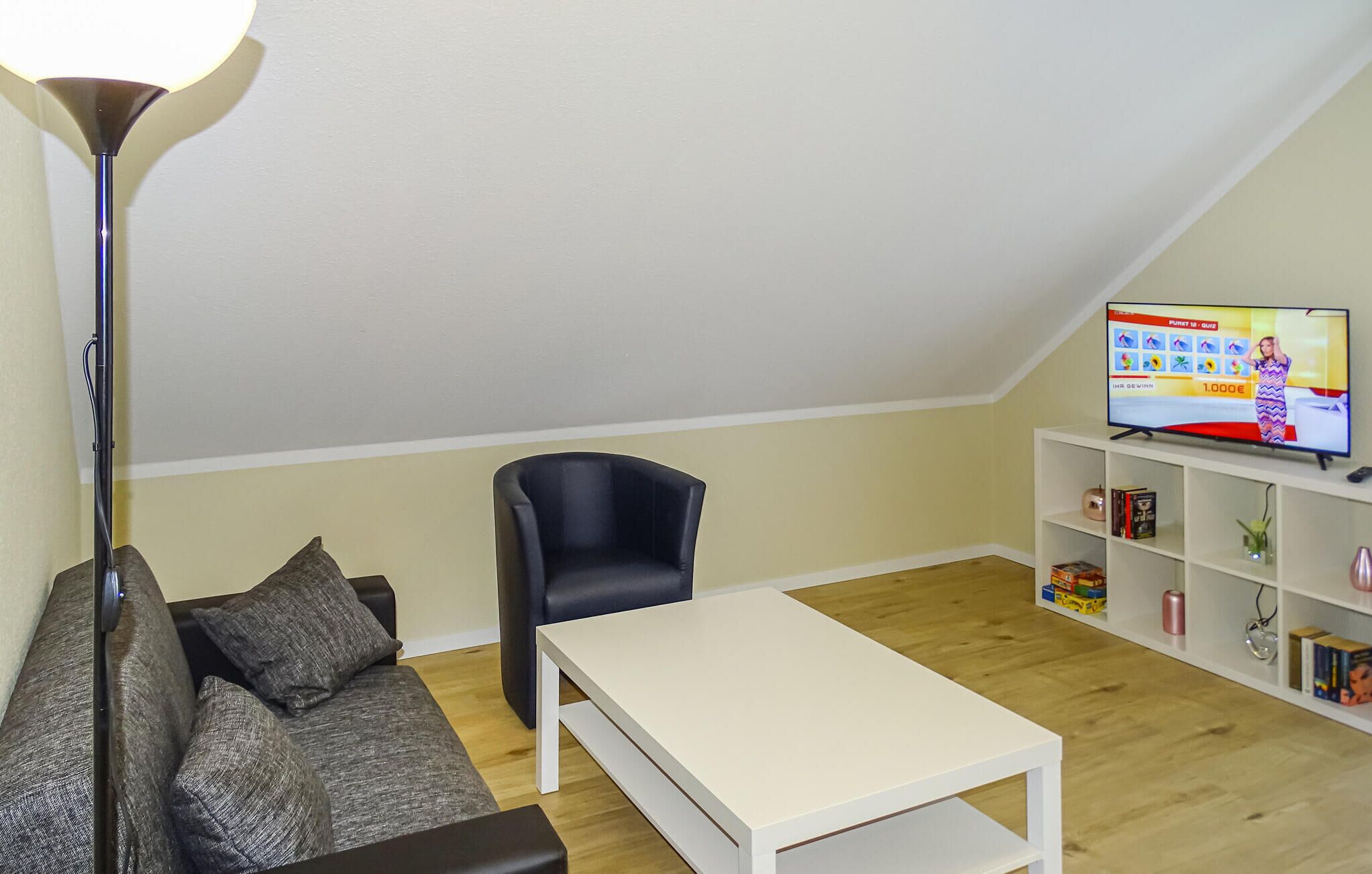 A living room with a sofa, a chair, a coffee table, a TV, and a bookshelf.