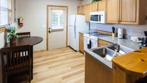 A compact kitchen with wooden cabinets, a microwave, a refrigerator, and a sink. - Charming  Cottage at Willow Creek Falls & Vineyard in Blue Ridge, GA (Blue Ridge)