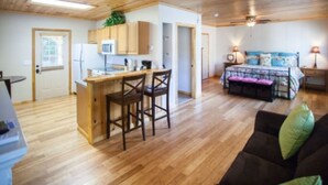 A compact living space with a kitchenette, a dining area, and a bedroom. - Charming  Cottage at Willow Creek Falls & Vineyard in Blue Ridge, GA (Blue Ridge)