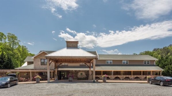 A two-story building with a covered entrance and a stone facade. - Charming Cottage at Willow Creek Falls & Vineyard in Blue Ridge, GA (Blue Ridge)