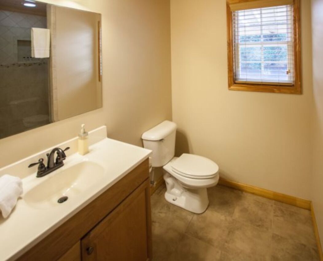 Ein Badezimmer mit Waschbecken, Spiegel, Toilette und Fenster.