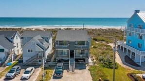 A coastal building with a balcony, a garage, and a view of the beach.