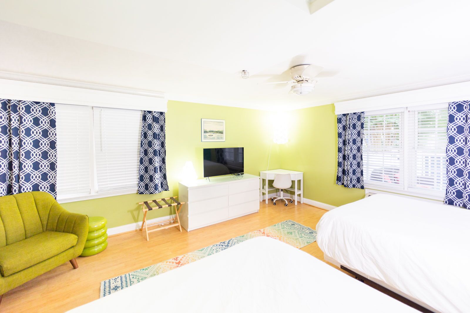 Un dormitorio con cama, escritorio, silla, televisión y ventilador de techo.