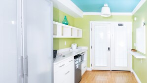 Een keuken met witte kastjes, een blauwgroene vaas en een witte plafondlamp.