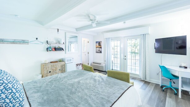 A bright, modern bedroom with a bed, a desk, and a TV. - Rehoboth Beach pet friendly hot tub Canalside Inn (Rehoboth Beach)