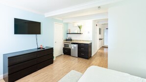A modern bedroom with a large bed, a dresser, and a flat-screen TV mounted on the wall. - Rehoboth Beach pet friendly hot tub Canalside Inn (Rehoboth Beach)