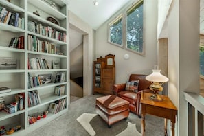 A cozy reading nook with a leather armchair, a small table with a lamp, and a bookshelf filled with books.