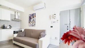 Un salon moderne avec un canapé, un coin cuisine et un tableau accroché au mur.