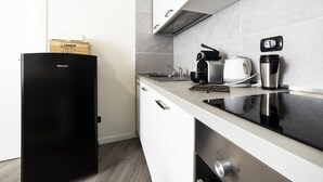 Une cuisine moderne avec un réfrigérateur noir, des armoires blanches, une cuisinière en acier inoxydable et une machine à café.