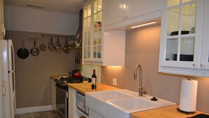 Una cocina con armarios blancos, un refrigerador de acero inoxidable, una estufa y un fregadero.