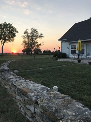 A stone wall, a grassy yard, and a building with a yellow umbrella. - Loft Apartment in this Rural Country Home  (Parker)