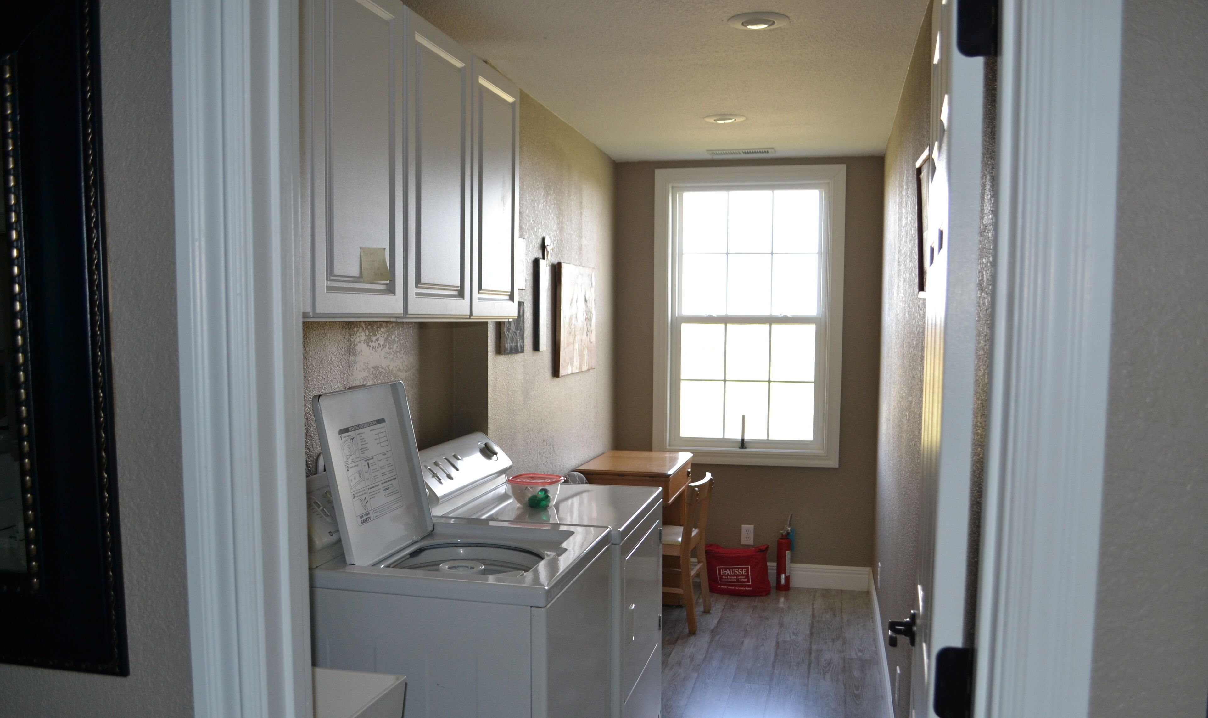 A laundry room with a washing machine, dryer, and a window providing natural light.
