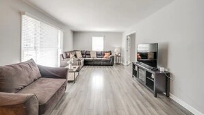 En moderne stue med en grå sofa, en mørk sofa og et tv-bord.