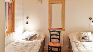 A bedroom with two single beds, a wooden chair, a mirror, and a radiator. - 3 bedroom stunning home in Särna (Särna)