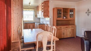 Una mesa de comedor de madera con sillas, una zona de cocina con armarios de madera y un radiador.