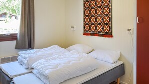 Una cama doble con ropa blanca, una ventana con cortinas y un tapiz decorativo en la pared.