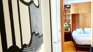 Une chambre à coucher avec un lit, des étagères en bois et une porte au motif noir et blanc.
