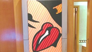 Une pièce avec un plancher en bois, une plante en pot et une œuvre d’art encadrée accrochée au mur.