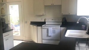 A kitchen with white cabinets, a black countertop, a stainless steel stove, and a ceiling fan. - Luxurious indoor/outdoor Family Paradise in downtown St Augustine (St. Augustine)