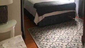 A bedroom with a bed, a ceiling fan, a nightstand, a lamp, a window with curtains, and a painting on the wall. - Luxurious indoor/outdoor Family Paradise in downtown St Augustine (St. Augustine)