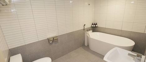 A bathroom with white tiled walls, a bathtub, a toilet, and a sink.