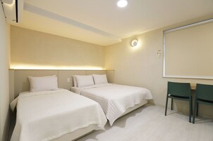 Habitación de hotel con dos camas, un escritorio y una silla.