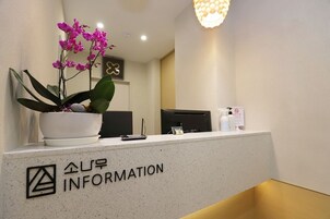 A reception desk with a potted orchid, a nameplate, and a few items on the counter.