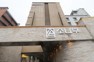 A building with a sign reading "Pine Tree" and a logo above it.