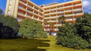 Ein mehrstöckiges Hotel mit symmetrischer Fassade, Balkonen auf jeder Etage und einem gepflegten Rasen davor.