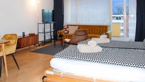 Ein Hotelzimmer mit einem Bett, einer Couch, einem Fernseher, einem Schreibtisch und einem Sessel.